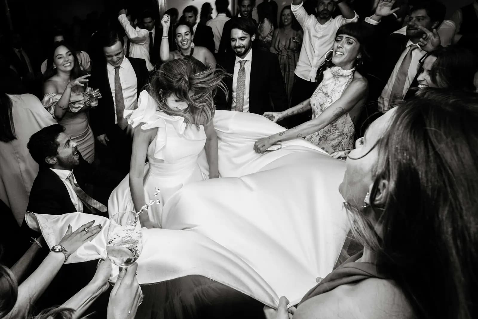 Guests lifting the bride into the air at the reception.